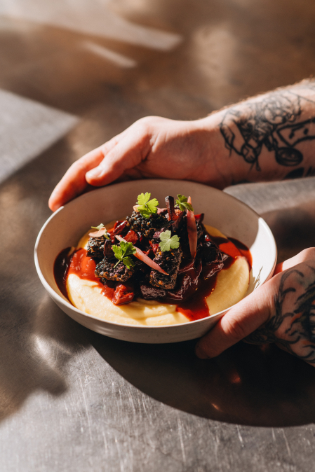 Silný bourguignon z kořenové zeleniny, tuřínová kaše, pošírovaná šalotka, tempeh z černé čočky